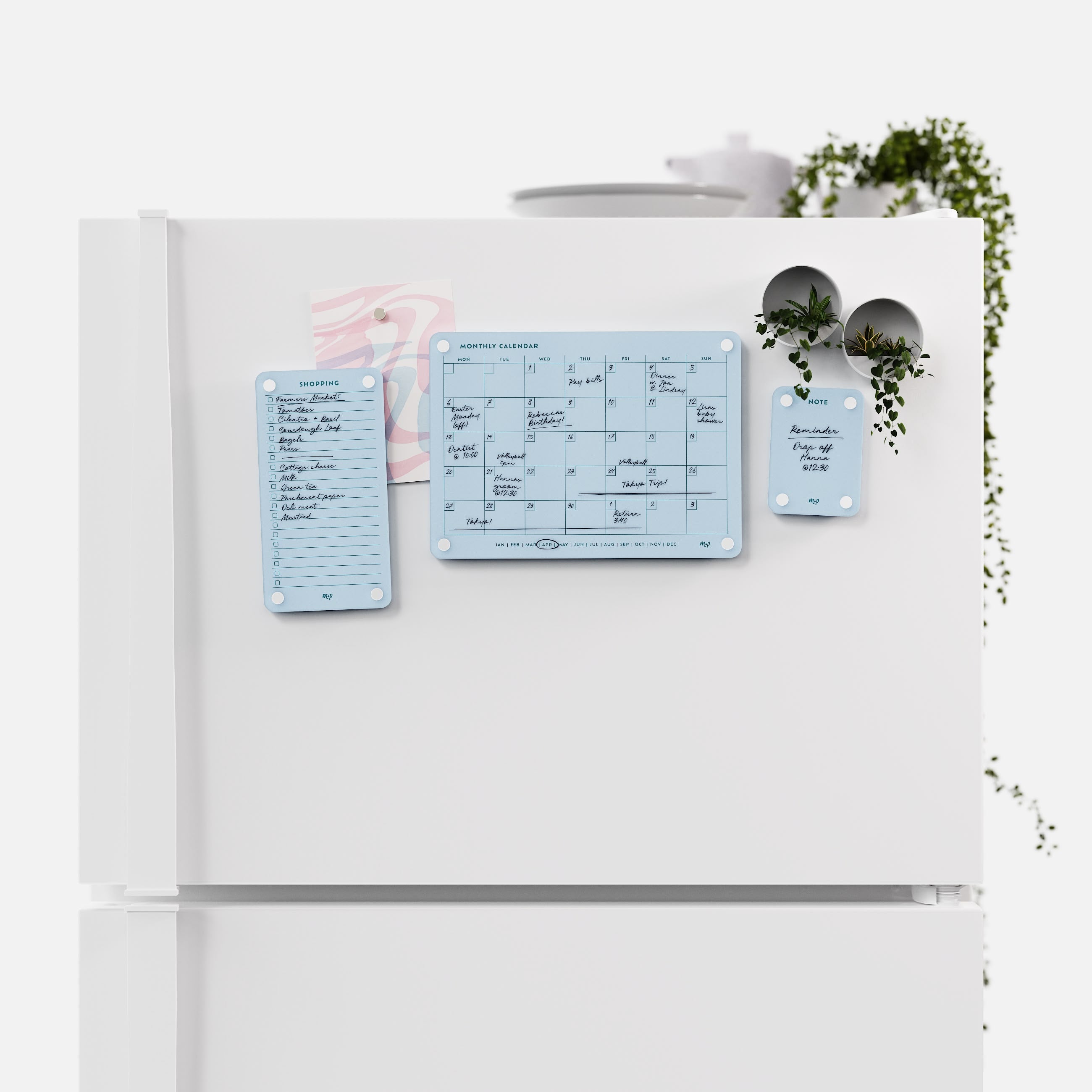 Vista blue shopping list, monthly calendar and note board arranged across a white fridge door
